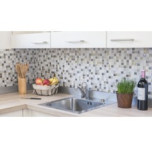 Küchenspüle mit Armatur, Mosaikfliesen und Küchenutensilien auf der Arbeitsplatte