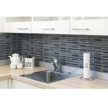 Küchenszene mit Spüle, Armatur, Arbeitsplatte, Geschirr und Küchenutensilien vor einer schwarzen Mosaikwand