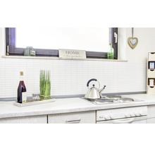 Küchenszene mit Kochfeld, Wasserkocher, Flasche, Glas und dekorativen Elementen.