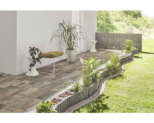 Gestalteter Gartenbereich mit Pflastersteinen, Pflanzkübeln und Sitzgelegenheiten