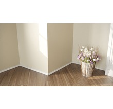 Zimmer mit Holzboden, weißen Wänden und einem Blumenarrangement in einem Korb