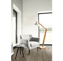 Heller Wohnraum mit Sessel, Stehlampe und Beistelltisch auf Bodenbelag