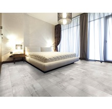 Helles Schlafzimmer mit Doppelbett, Nachttisch, Vorhängen und Bodenfliesen in Holzoptik.