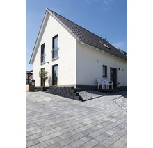 Außenansicht eines Wohnhauses mit Pflastersteinen, Treppenstufen und Terrasse