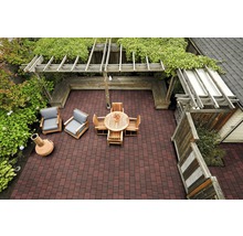 Draufsicht auf eine Terrasse mit Pflastersteinen, Holzmöbeln, einer Pergola und Grünpflanzen.