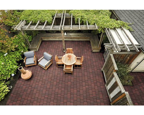 Draufsicht auf eine Terrasse mit Pflastersteinen, Holzmöbeln, einer Pergola und Grünpflanzen.