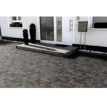 Einfahrt mit Pflastersteinen in Fischgrätmuster vor einem Wohnhaus.