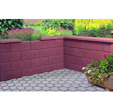 Ecke einer Gartenmauer aus Betonsteinen mit Steinabdeckung und Pflastersteinen im Garten