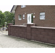 Eine Gartenmauer aus Mauersteinen vor einem Haus.