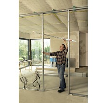 Mann montiert eine Trennwand mit Metallprofilen im Rohbau.