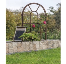 Dekorativer Garten mit Metallfensterrahmen, Waschbrett und Steinmauer.