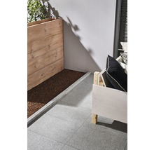 Szene mit Holzpflanzkasten, Sitzgelegenheit und grauen Terrassenplatten.