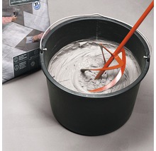 Fliesenkleber wird mit einem Rührwerk in einem Eimer angerührt.