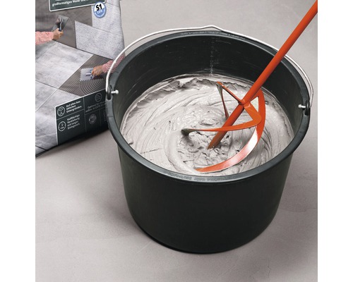Fliesenkleber wird mit einem Rührwerk in einem Eimer angerührt.