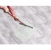 Person verfugt Fliesen mit einem Fugenmörtel und einem Fugengummi.