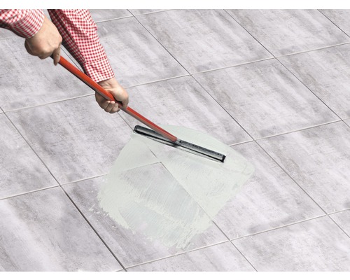 Person verfugt Fliesen mit einem Fugenmörtel und einem Fugengummi.