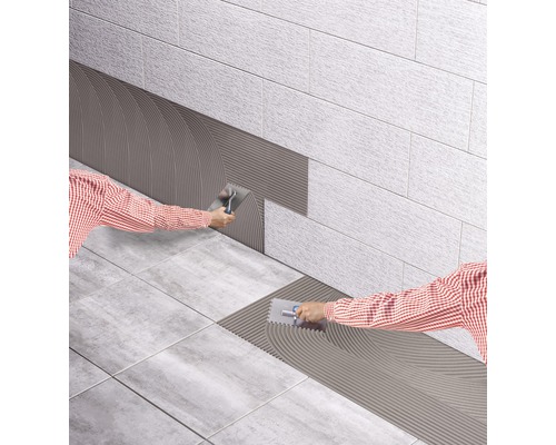 Fliesenleger trägt Fliesenkleber auf Wand- und Bodenfliesen auf