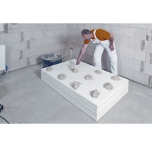 Ein Mann bringt Mörtel auf Dämmplatten in einem Innenraum auf.