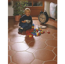 Kind spielt mit Bauklötzen auf einem Boden mit achteckigen Fliesen