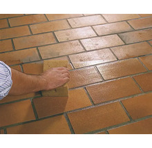 Person reinigt Bodenfliesen mit einem Schwamm