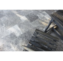 Bodenbelag aus Natursteinfliesen und Holzstuhl