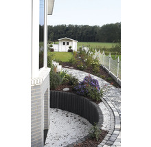 Gartenszene mit Gartenhaus, Weg aus Pflastersteinen und dekorativer Beetbegrenzung