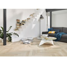 Wohnzimmer mit hellem Fischgrätparkett, Treppe mit Büchern und grauer Couch