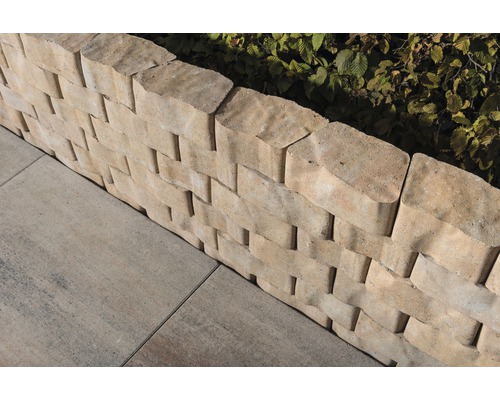 Detailansicht einer Trockenmauer aus Betonsteinen mit Pflastersteinen im Garten