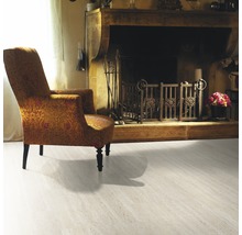 Wohnzimmer mit Sessel, Kamin und hellem Bodenbelag.