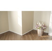 Dekoratives Blumenarrangement in einem Raum mit Holzboden und hellen Wänden.