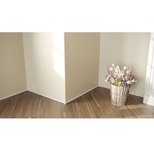 Eckansicht eines Raumes mit Holzboden, Sockelleisten und einem Blumenarrangement in einem dekorativen Topf