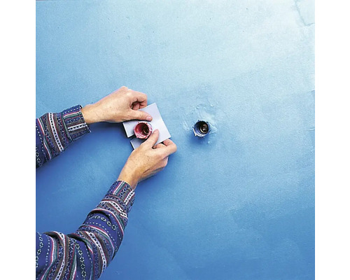 Eine Person befestigt Rosetten an einer Wand an einem Sanitäranschluss.