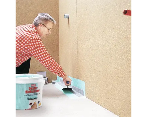 Eine Person trägt Dichtschlämme mit einer Kelle auf, abgedichtet mit Dichtband, Eimer im Vordergrund.