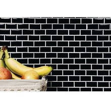 Wand mit schwarzen rechteckigen Fliesen und Obstkorb