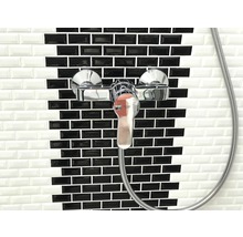 Duscharmatur vor einer Wand mit schwarzen und weißen Fliesen