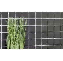 Dekorative Kunstpflanze vor einer Wand aus Fliesen