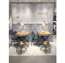 Ausstellungsraum mit zwei Tischen und Sitzgelegenheiten, gefliestem Hintergrund und Beleuchtung.