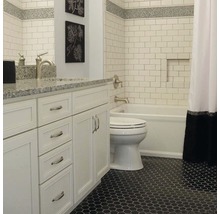 Badezimmer mit weißen Fliesen, Waschtisch und schwarzem Mosaikboden.