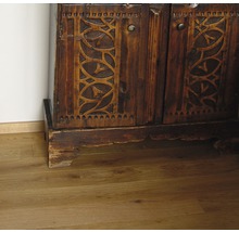 Detail eines Holzschranks mit geschnitzten Türen auf einem Holzboden