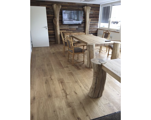 Esszimmer mit Holzboden, Tisch mit Baumstammfüßen, Holzstühlen und TV an einer Holzwand