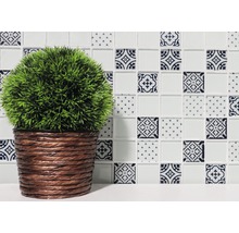 Dekorative Fliese mit Muster und Kunstpflanze im geflochtenen Topf