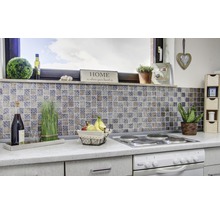 Küchenszene mit Mosaikfliesen, Kochfeld, Dekorationen und Lebensmitteln auf einer Küchentheke.