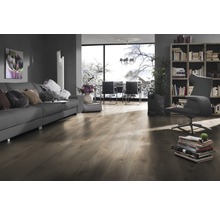 Wohnzimmer mit Sofa, Sessel, Bücherregal und Laminatboden.