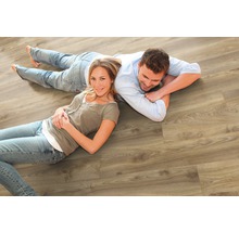 Ein Paar liegt auf einem hellen Holzlaminatboden.