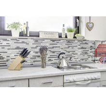 Küchenszene mit Mosaikfliesen, Kochfeld, Spüle und verschiedenen Küchenutensilien