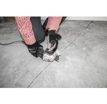 Eine Person schneidet mit einem Winkelschleifer eine Fuge in einen Betonboden.