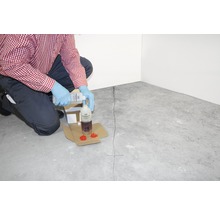 Anwender gießt Rissinjektionsmittel in eine Flasche für die Rissreparatur