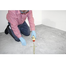 Mann verschließt Fuge im Boden mit Dichtmasse