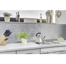 Helle Küche mit Mosaikfliesen, Kochfeld, Wasserkocher und dekorativen Elementen.