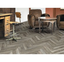 Interieuransicht mit einem Bodenbelag im Fischgrätmuster, einem Sessel, einem Tisch und Möbeln